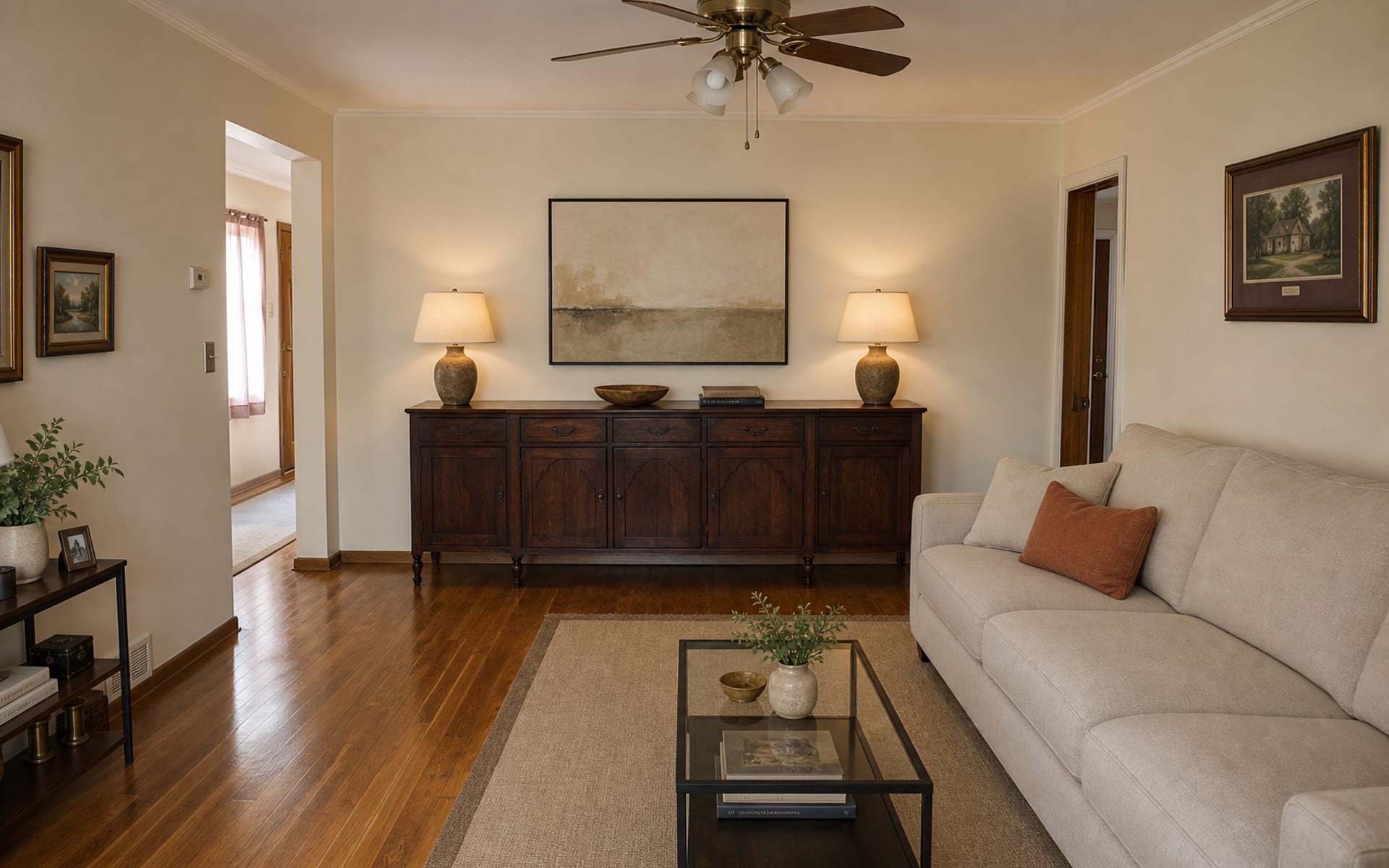 Same living room with the antique sideboard simplified, a modern oatmeal linen sofa, warm lamps, and abstract art.