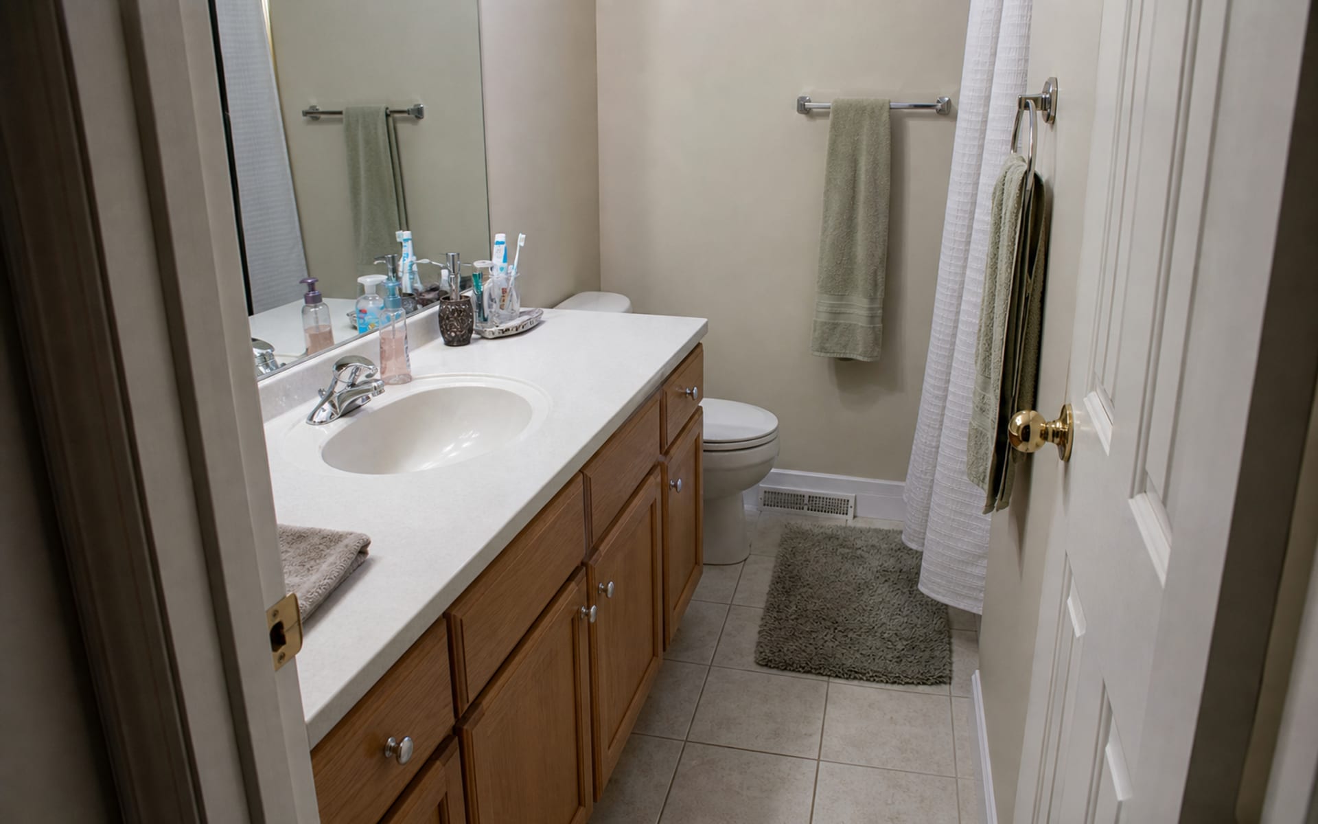 Small bathroom with an oversized vanity crowding the toilet path, bulky cabinet doors, and poor mirror lighting.